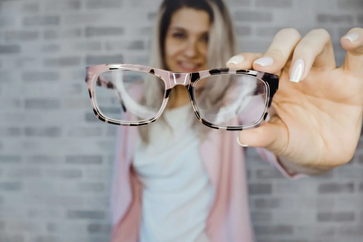 Frau hält Brille hoch – Kontaktlinsenträger brauchen oft spezielle Augentropfen